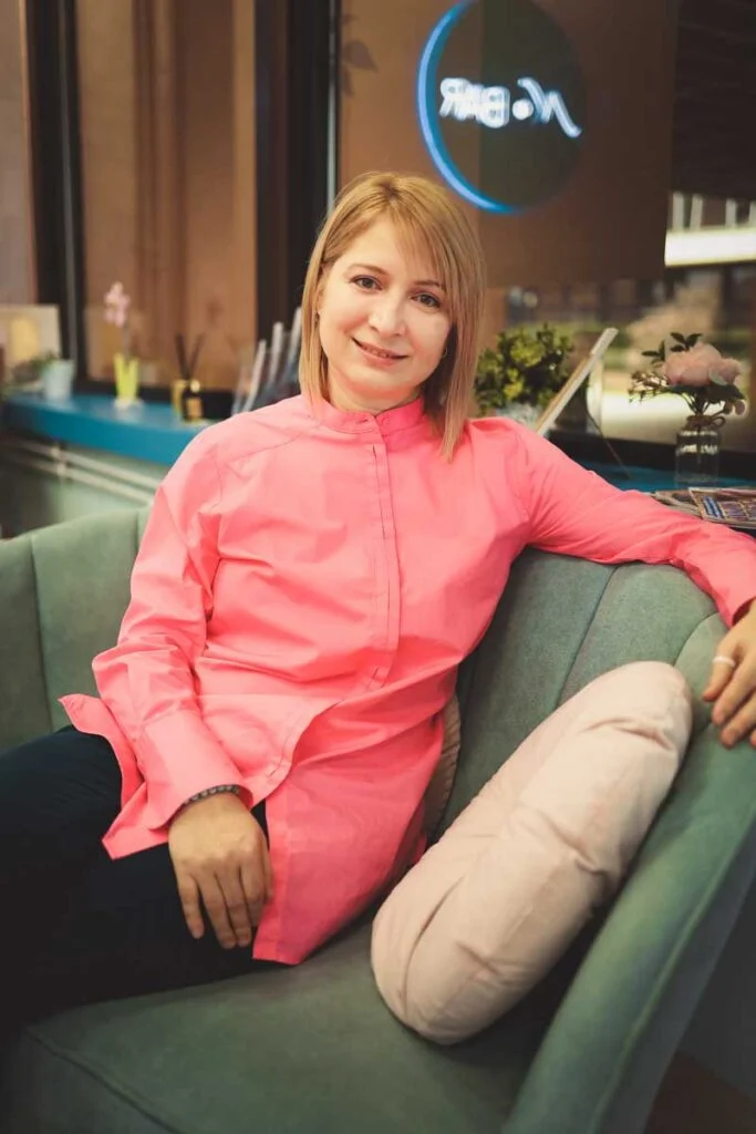 Nika Mak performance mindset coach and mentor sitting on a sofa in a relaxed and calm pose