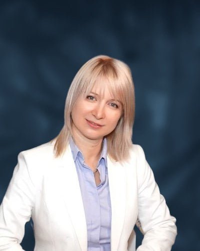 Nika Mak performance mindset coach white jacket with dark blue green background